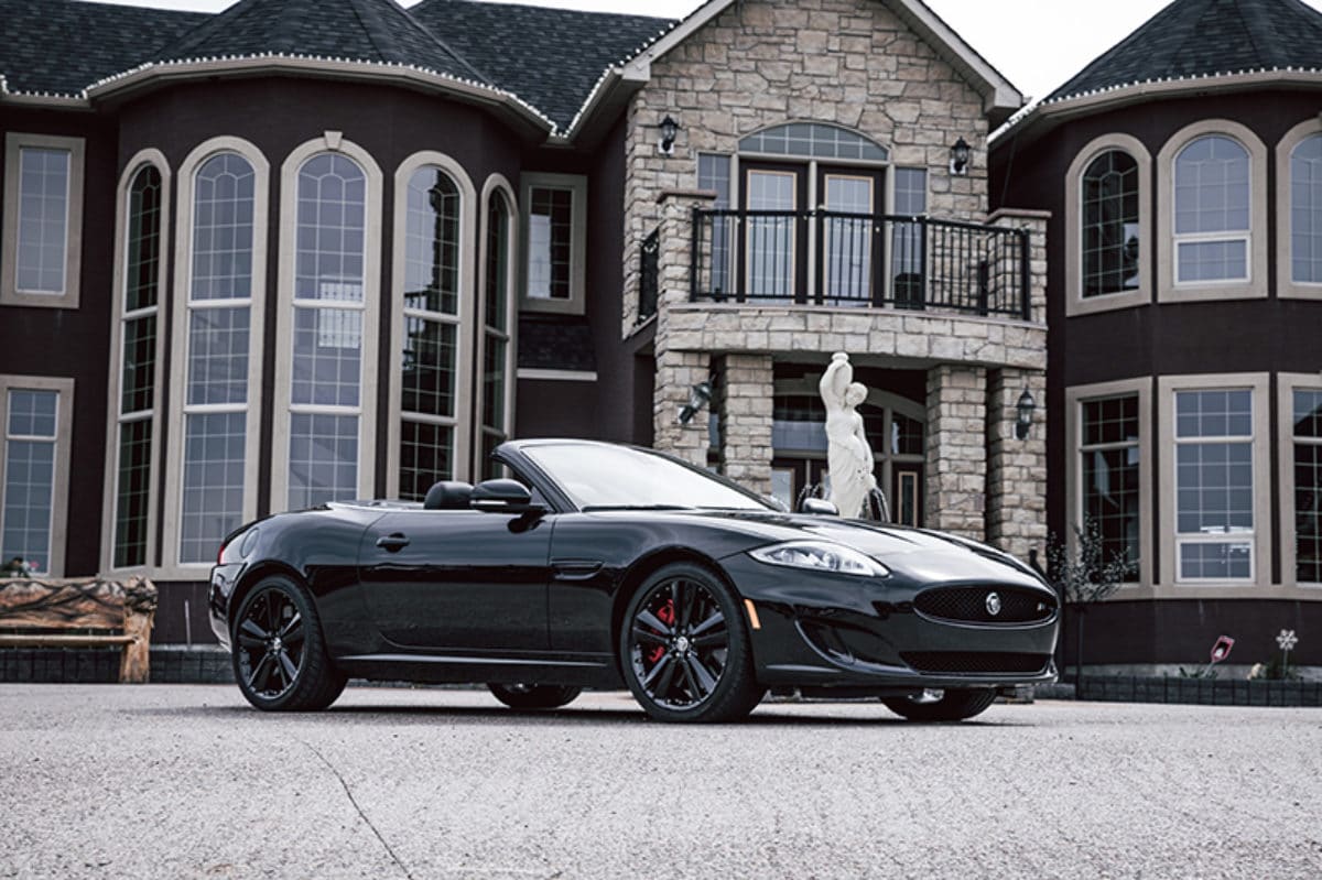 A convertible parked in front of a mansion