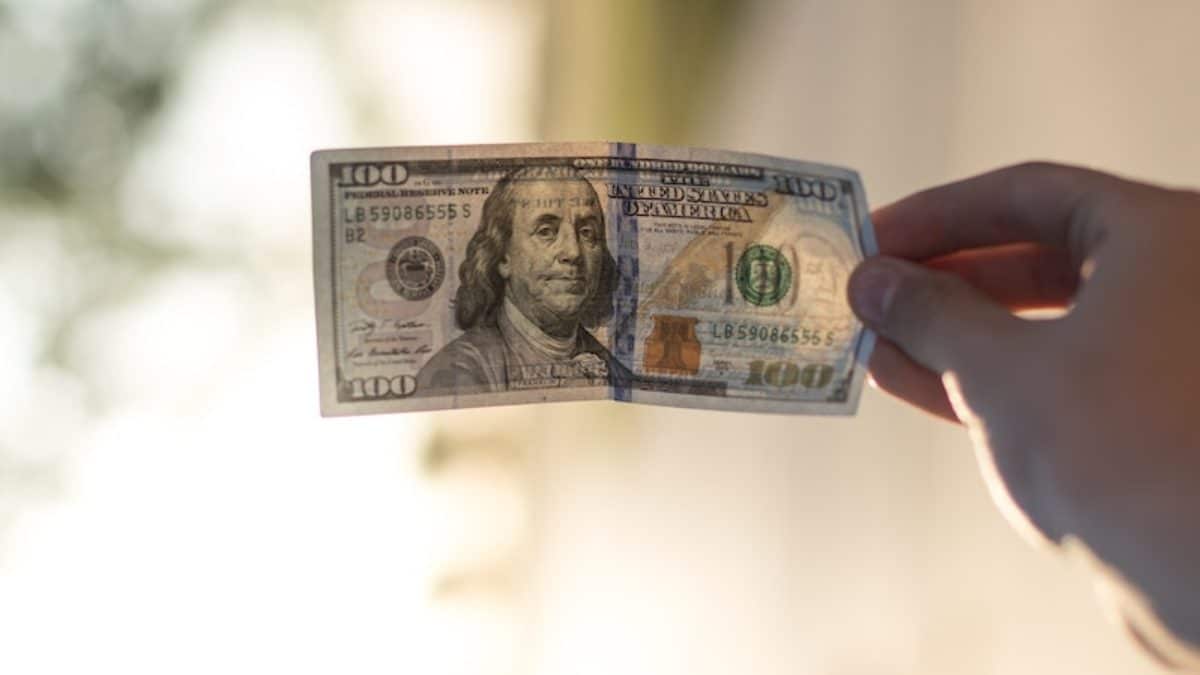 A $100 bill held in a hand
