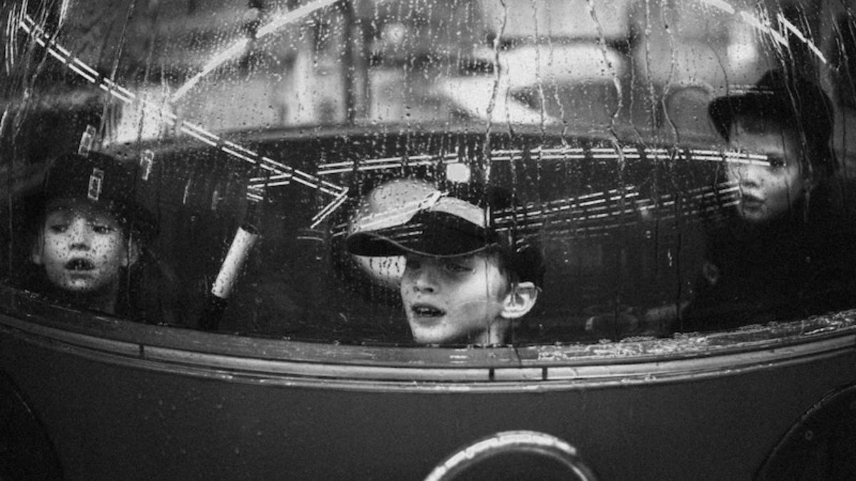 Children looking out through rain-streaked window
