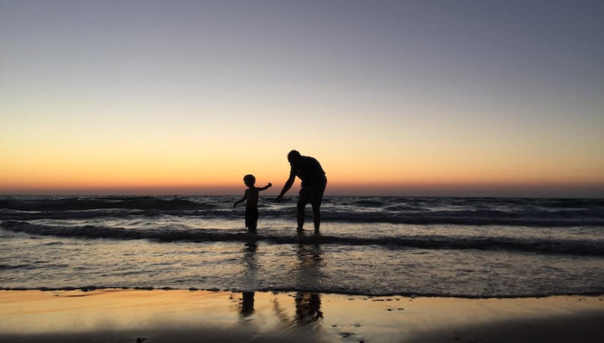 Grandfather with grandson wading at the beach