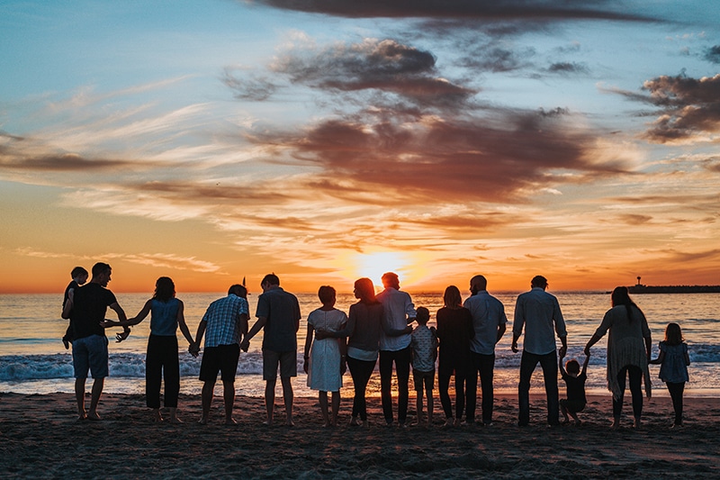 A large family standing on the beach at sunset--family is one of our greatest assets under management